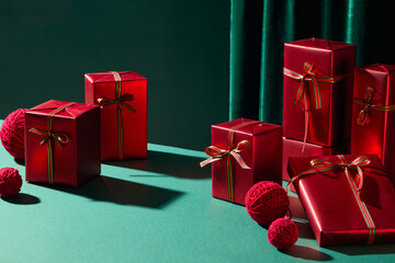 Red present boxes of different shapes are arranged neatly on a green tabletop. Advertising scene creates a warm holiday spirit suitable for festive graphics.