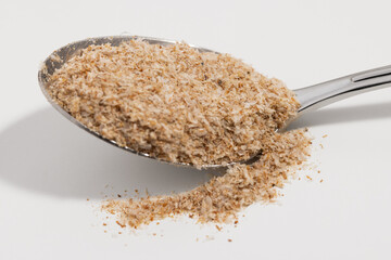 Psyllium on a silver spoon on a white background