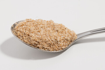 Psyllium on a silver spoon on a white background