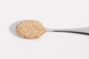 Psyllium on a silver spoon on a white background