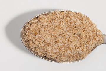 Psyllium on a silver spoon on a white background