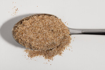 Psyllium on a silver spoon on a white background