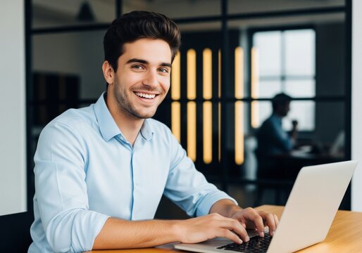 Young man smiling while working on a laptop in a modern office environment. - Powered by Adobe