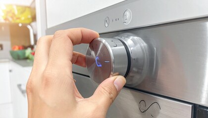 Close-up of hand adjusting stainless steel oven knob with blue-lit digital display, set in a modern kitchen with fruit bowl in background, highlighting smart cooking technology and user interaction.