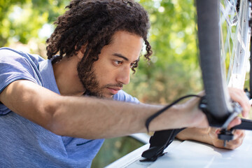 man is adjusting his bike on the car roof
