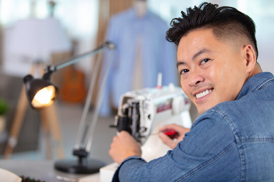 concentrated young male tailor sewing in workshop
