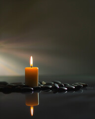 burning candle on a dark background, with spa stones