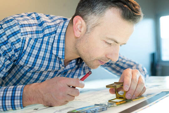 man inspecting a cyan test print using magnifying glass