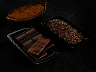 Experience the artistry of handcrafted chocolate, showcasing cocoa beans alongside rich, decadent bars and crunchy nibs, all set against a dramatic black backdrop