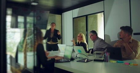 African American businesswoman answering questions during team presentation while colleagues engage and observe in modern office conference room