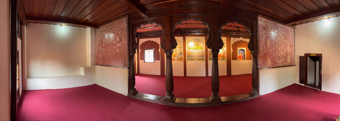 Traditional wooden-pillared hall inside Nana Fadnavis Wada, featuring preserved murals, red carpets, and classic Maratha architectural elements. © Jatin