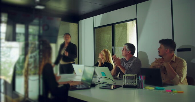 African American businesswoman answering questions during team presentation while colleagues engage and observe in modern office conference room