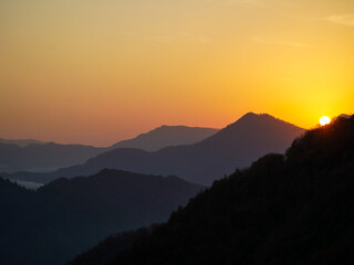 A mountain range at sunset with a golden sky.
