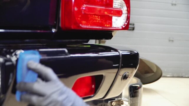 Car service worker applying nano coating on car detail. Specialistic ceramic coating liquid powder on to sponge by unrecognizable professional. Car detailing process. Auto Detailing. Car body repair. 