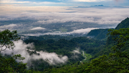 a view of a lush green mountain landscape with fog or low-hanging clouds in the valleys below. Galunggung, Tasikmalaya, West Java, Indonesia