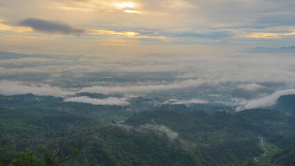 a view of a lush green mountain landscape with fog or low-hanging clouds in the valleys below. Galunggung, Tasikmalaya, West Java, Indonesia