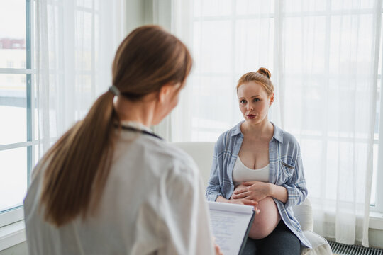 Female doctor examining pregnant woman in doctor office. Pregnant girl patient have consultation in hospital. Gynecologist doctor consulting patient about pregnancy. Visit to doctor medical checkup