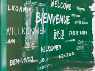 welcome text in multiple languages of various country in a wall green