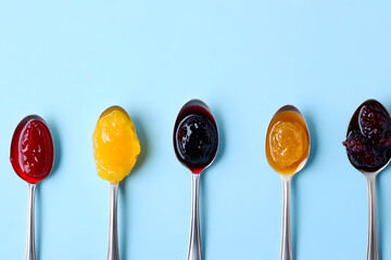Spoons filled with different types of jams for tasting - expressing the variety and richness of homemade preserves blue background