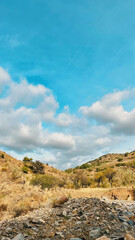 Hills with a white house, grasses and trees under blue sky with some clouds. Malaga, Andalusia, Spain.