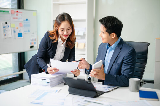 Asian businessman and woman workers talking on the smartphone and using laptop Professionals in Teamwork Finance, Marketing