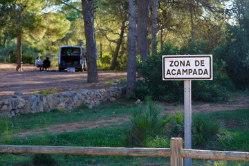 zona de acampada. señal de area para tiendas de campaña y motor homes con furgoneta camper y personas comiendo al fondo