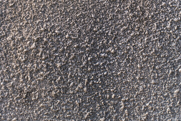 Gray plaster with a textured appearance of small pebbles embedded in the cement layer. Background. Close-up.