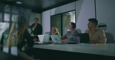 African American businesswoman presenting key data to attentive colleagues during corporate meeting in modern office conference room
