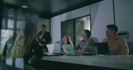 African American businesswoman presenting key data to attentive colleagues during corporate meeting in modern office conference room