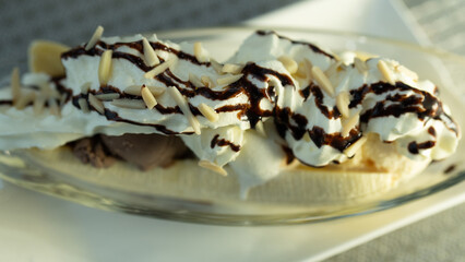 Gourmet chocolate and vanilla banana split with scoops of creamy ice cream and a sliced fresh banana on a bed of whipped cream drizzled with chocolate sauce