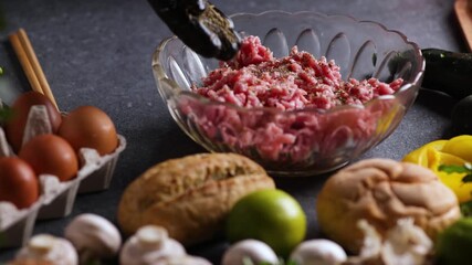 Chef sprinkling spices on minced meat in crystal bowl with mushrooms lime buns parsley and eggs