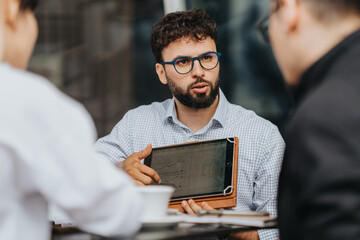 Group of coworkers having a corporate meeting while using a tablet to share data insights, fostering teamwork and collaboration.
