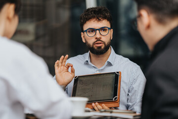 Businesspeople engaged in a discussion at an outdoor workspace with a displayed tablet for referencing.