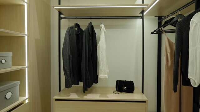 Slow stabilized walkthrough of a modern open wardrobe with neatly arranged clothing, soft lighting, wooden shelves, and minimalistic interior design elements, captured in a calm and clean aesthetic.
