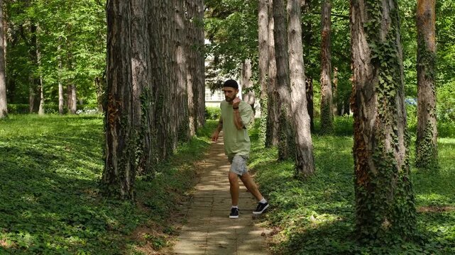 A man dances on a narrow forest path, snapping his fingers and stepping back rhythmically among tall summer trees. The concept expresses rhythm, coordination, confidence, and natural freedom