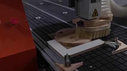 CNC machine mills a wooden workpiece, the operator controls the process using a hand-held remote control. Modern high-precision woodworking production and automation.