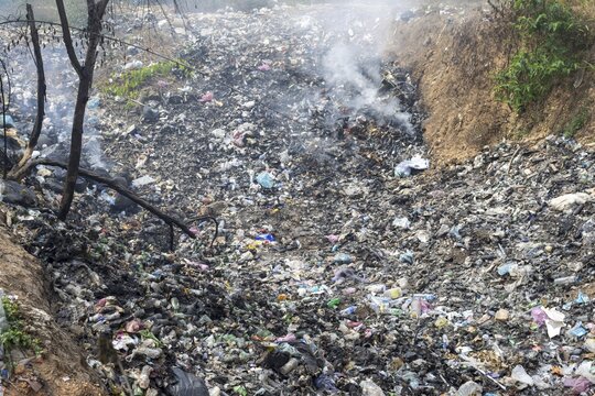 Coking rubbish dump, rubbish pit with waste and plastic rubbish, karst landscape near Vang Vieng, Vientiane province, Laos