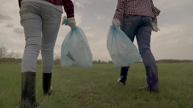 volunteers collect garbage in garbage bags, protect nature from pollution, collective teamwork waste disposal, charity work of activists, clean nature, eco, people in rubber boots walk along the road.