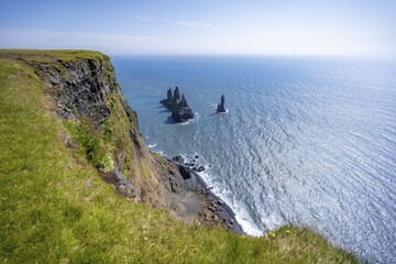 Steep coast, view from steep cliff to the rocks Reynisdrangar in the water, at Reynisfjara beach, Vik, South Iceland, Iceland