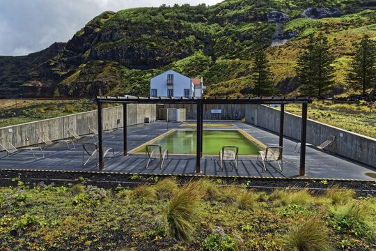 Thermal pool in the middle of nature, surrounded by mountains and a white house, Termas da Ferraria, Sao Miguel Island, Azores, Portugal