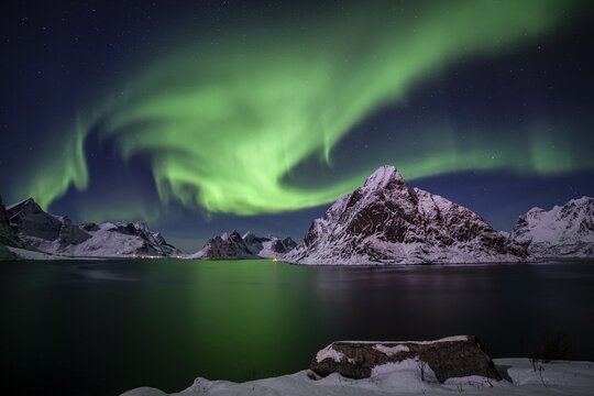 Green northern lights reflected in fjord, steep mountains, aurora borealis, winter, Reine, Moskenesoya, Lofoten, Norway