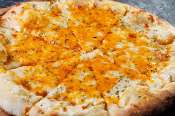 Cheesy Baked Pizza On Wooden Paddle Served On Dark Textured Tabletop