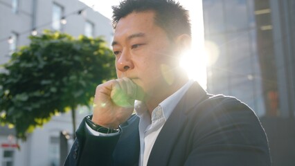 Confused thoughtful Asian Korean 40s business man Chinese Japanese businessman thinking puzzled hesitate looking at camera deciding think create plan decision idea middle-aged male in sunny city sun