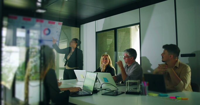 African American presenter smiling after delivering business presentation while colleagues respond positively in team meeting environment