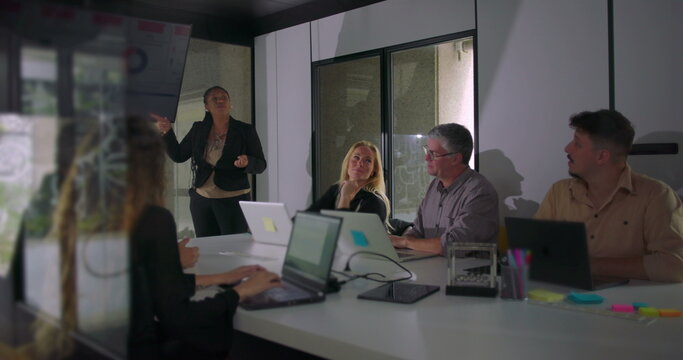 African American professional presenting during team meeting while colleagues observe digital screen in well lit corporate boardroom