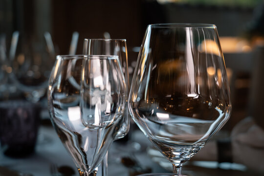 Three wine glasses are on a table, with one of them being a wine glass