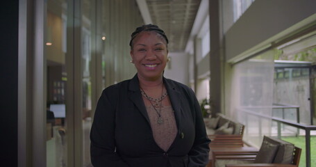 Fototapeta premium African American woman smiling confidently in corporate hallway friendly and professional expression welcoming demeanor in business environment