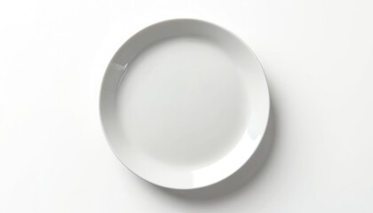 White ceramic plate sits empty on a clean white surface. This simple dish is perfect for food related concepts presentation. View from above.