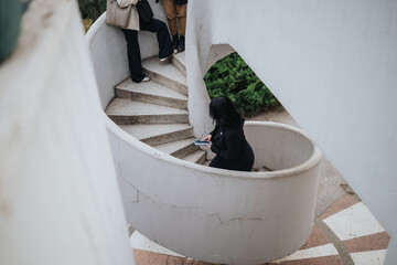 A group of young professionals gathers around a curved concrete staircase in a bright, contemporary space. One woman descends while others pause, capturing a casual yet productive outdoor moment.