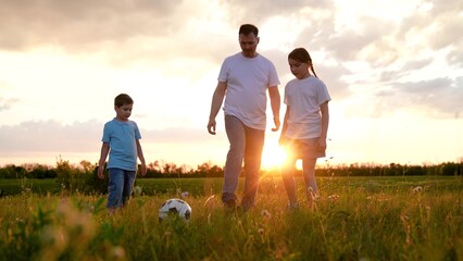 Dad son daughter Child kicks ball. Happy family playing football. Family have fun playing soccer ball on lawn in park. Young family sport soccer team playing outdoor. Dad kids play together, teamwork